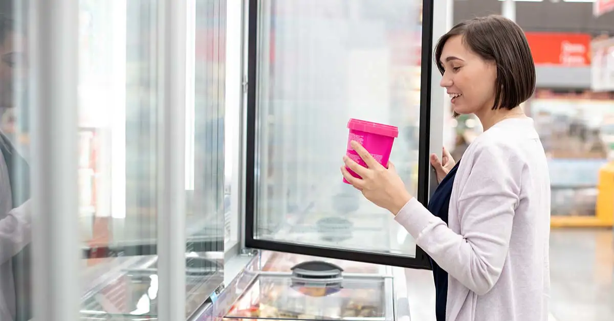 A person holding an ice cream in a grocery store
